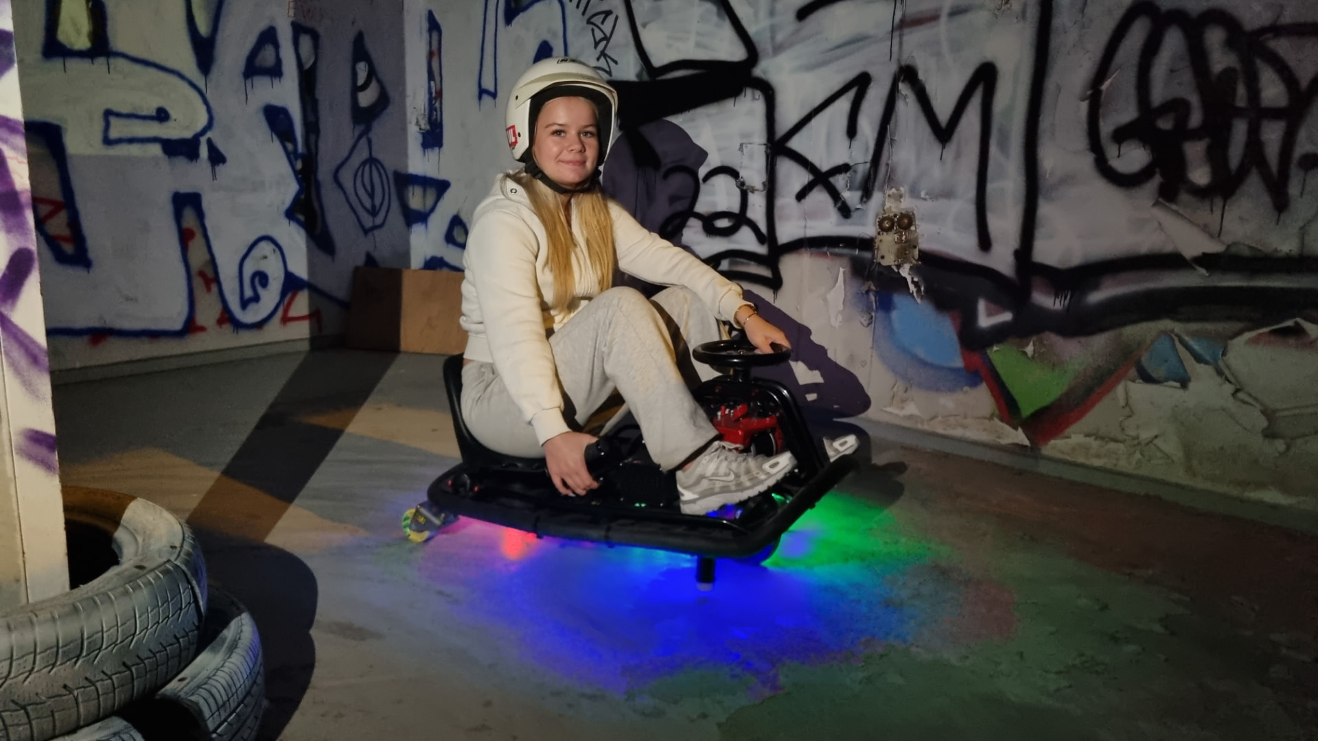 Kvinde i hvid racerdragt på en neonoplyst driftkart
